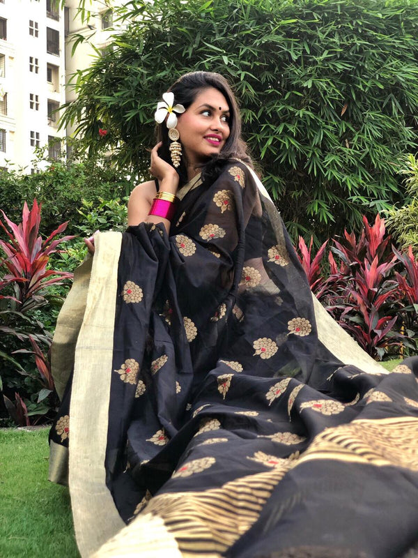 Genda Chanderi Sari is a Black handwoven Chanderi sari with golden 'genda phool' motifs and red meena. The sari is a simple six yards of flowers spread over a dark night of the wedding fireworks